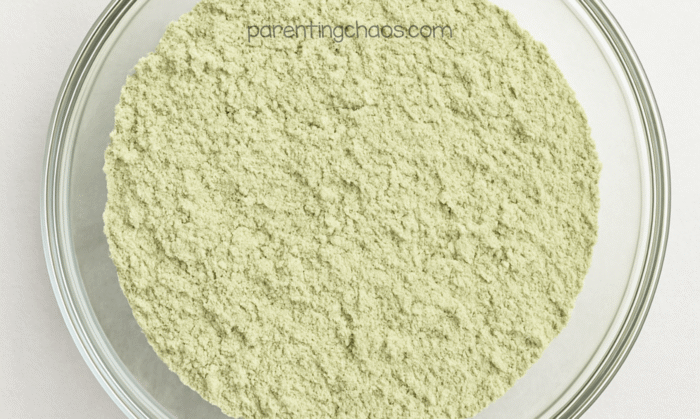 A bowl of flour and green powder fully mixed into a pale green blend.