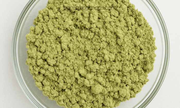 Green moon sand mixture after oil is combined, forming crumbly green clumps.