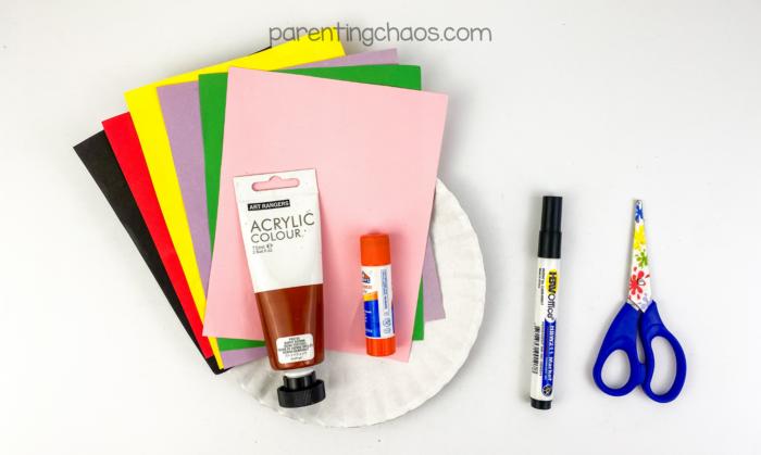 Supplies for treasure chest paper plate craft including colored paper, acrylic paint, glue stick, marker, scissors, and paper plate.