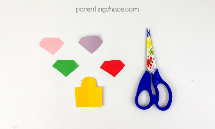 Colored paper gems and lock pieces cut out for decorating a kids treasure chest paper plate craft.