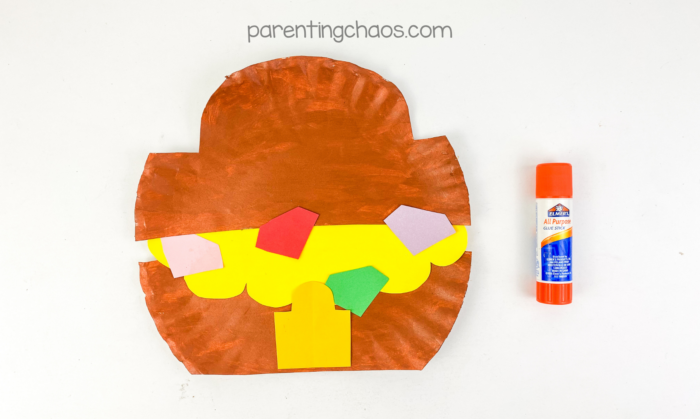 Treasure chest paper plate craft decorated with colorful paper gems and a lock.